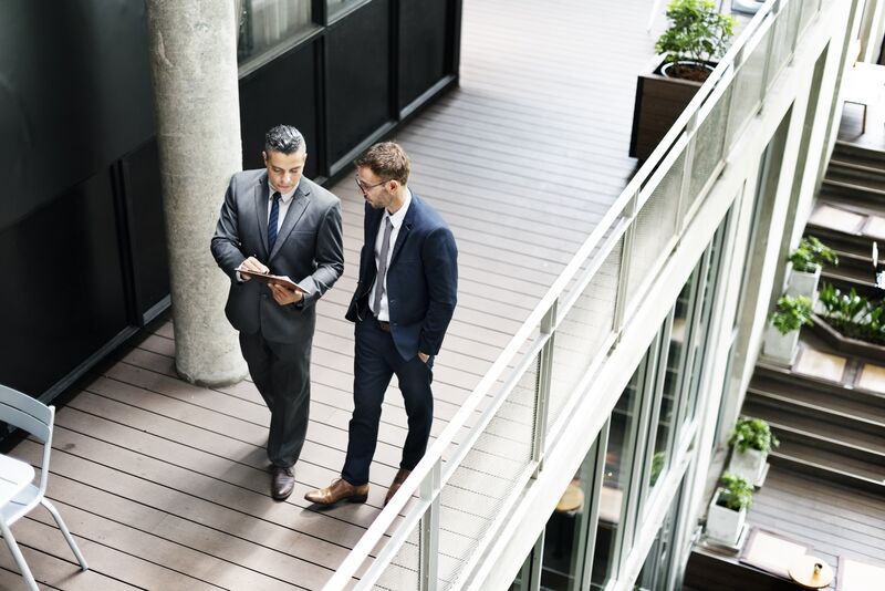 Businessmen walking and looking at paperwork.