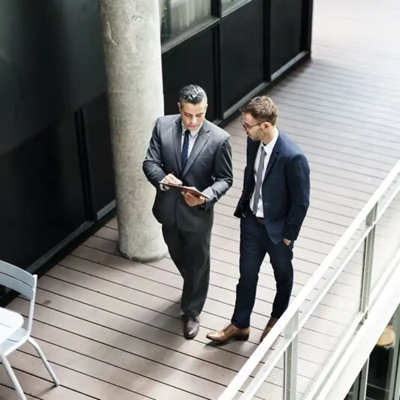 Businessmen walking and looking at paperwork.