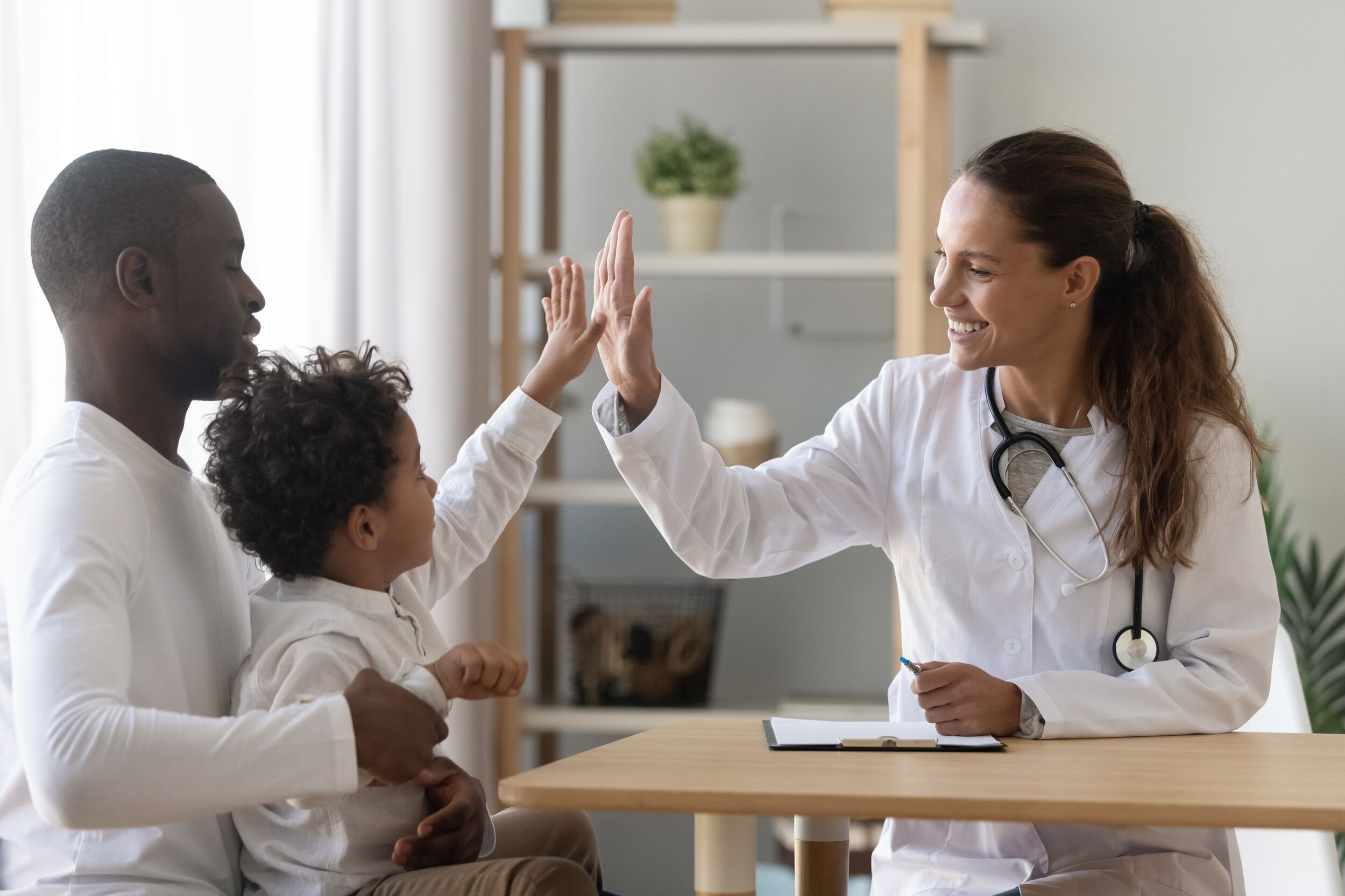 Pediatrician welcomes small kid patient and his dad at medical check up appointment