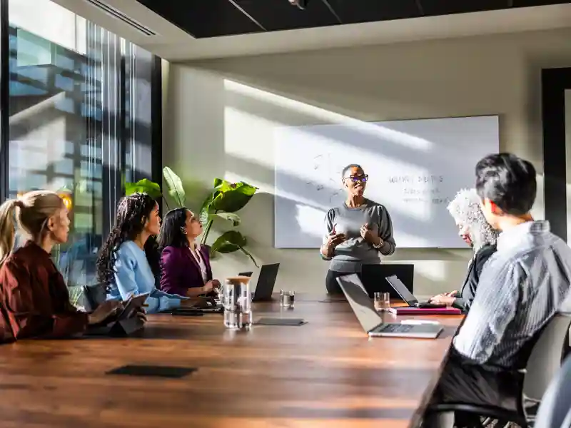 A team leader gives a presentation to a small group of employees in a conference room.