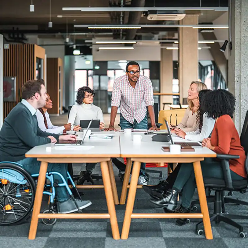 A team leader guides a diverse team of coworkers in a lively discussion.
