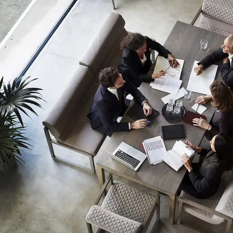 Business people wearing dark suits having a meeting at a conference table.