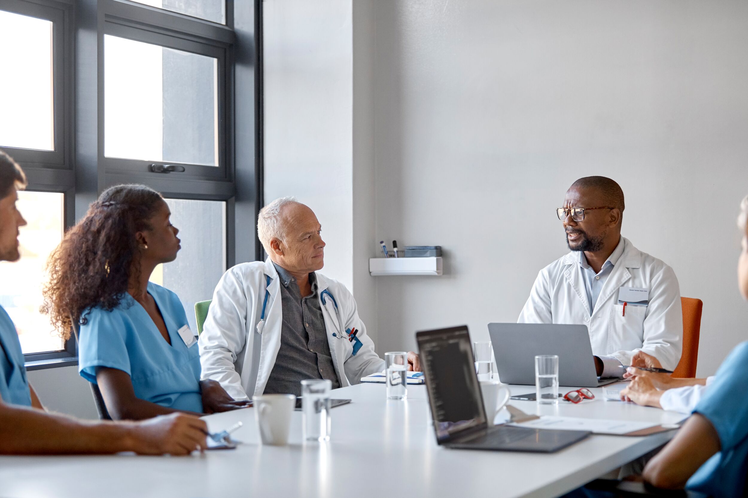 Doctor discussing with colleagues during meeting.