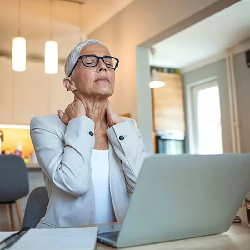An older woman suffers the effects of menopause while working from home.