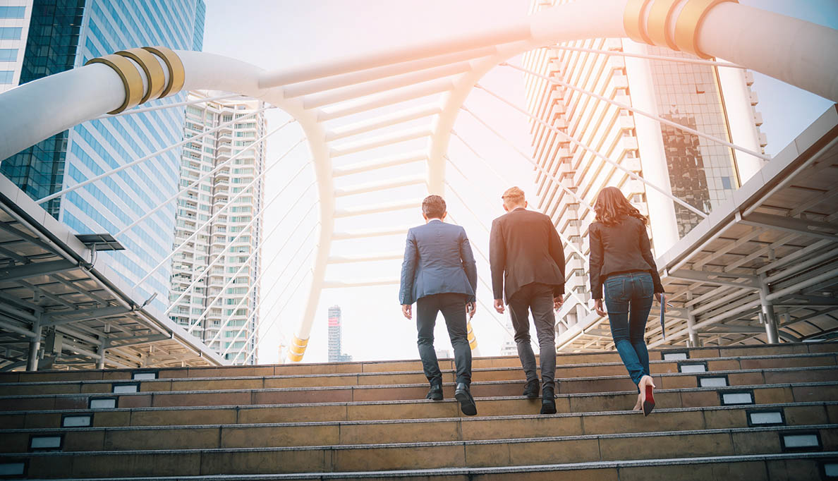 Three people walking up staris.