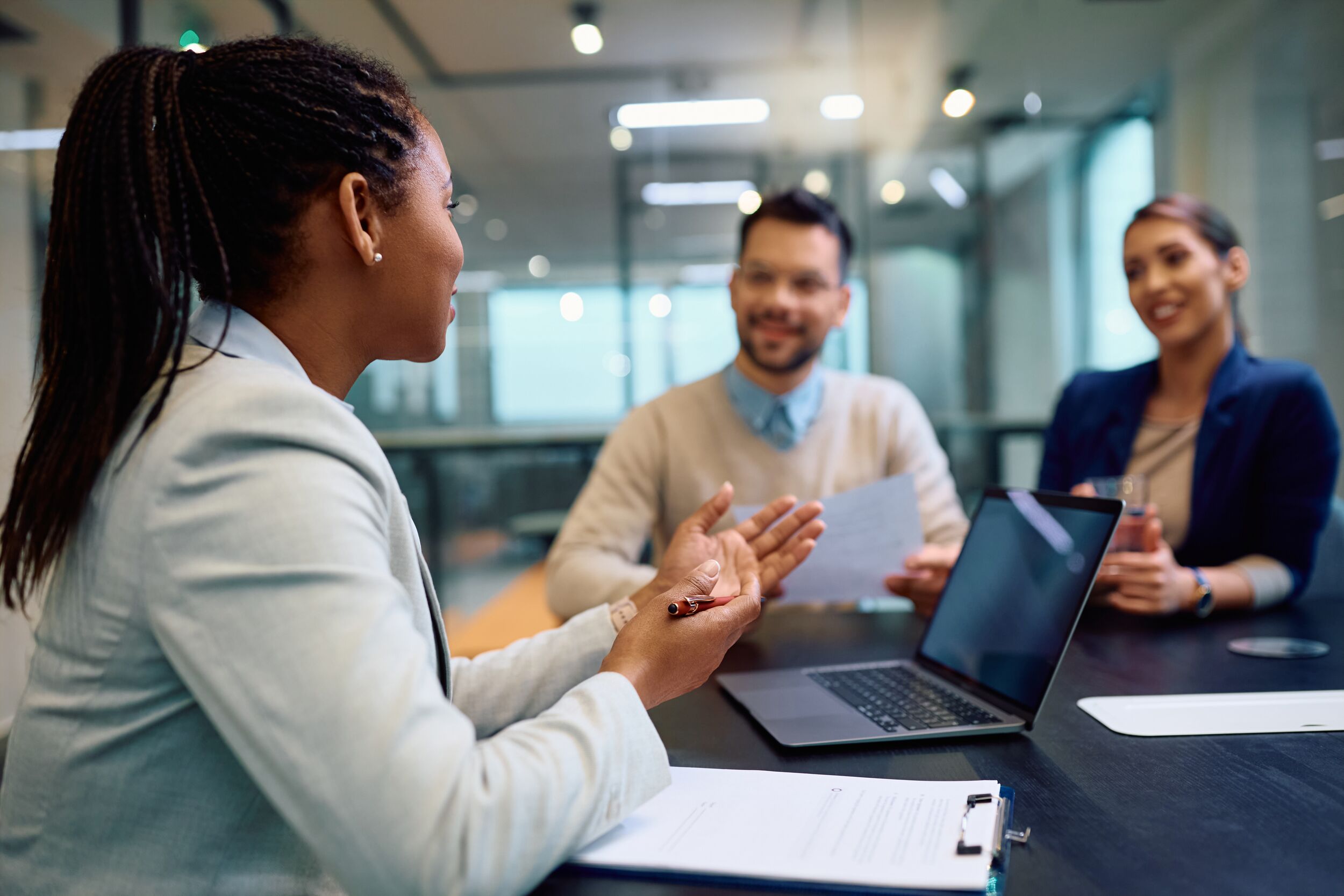 Female advisor speaking with male and female client at a table.