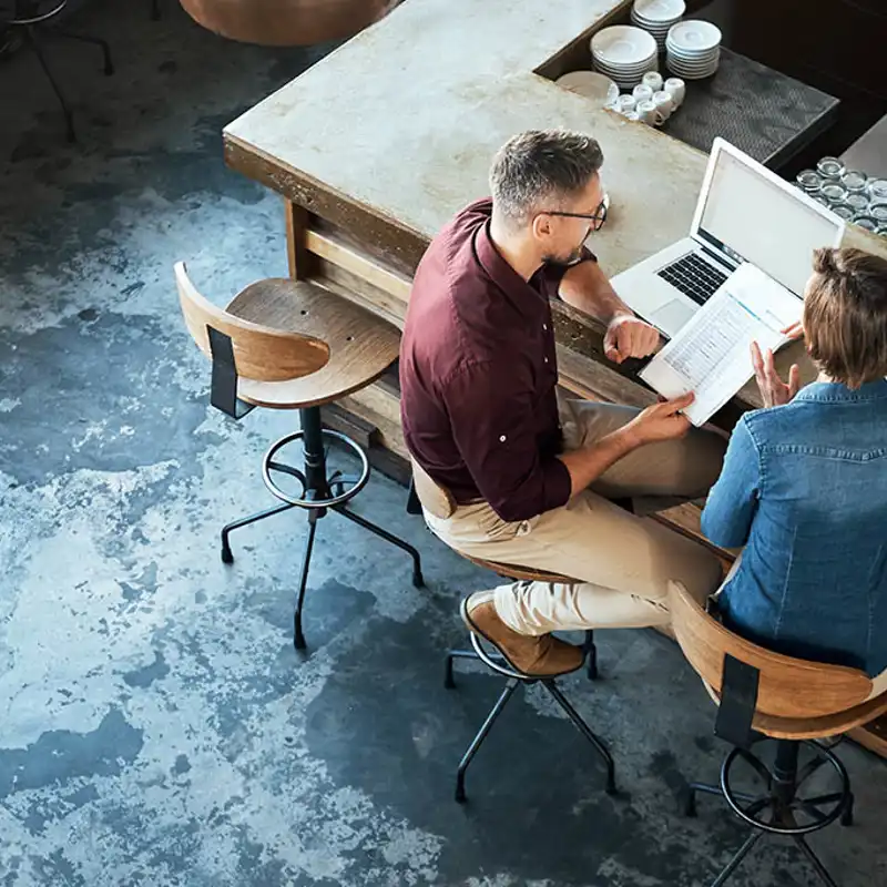 Two people looking over a financial sheet while seated at a bar.