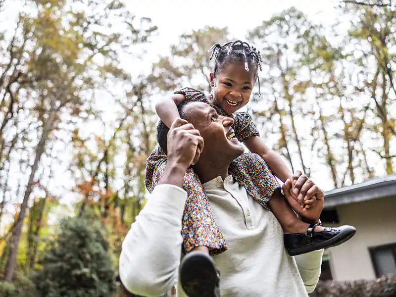 A young girl enjoys a ride on her father's shoulders.