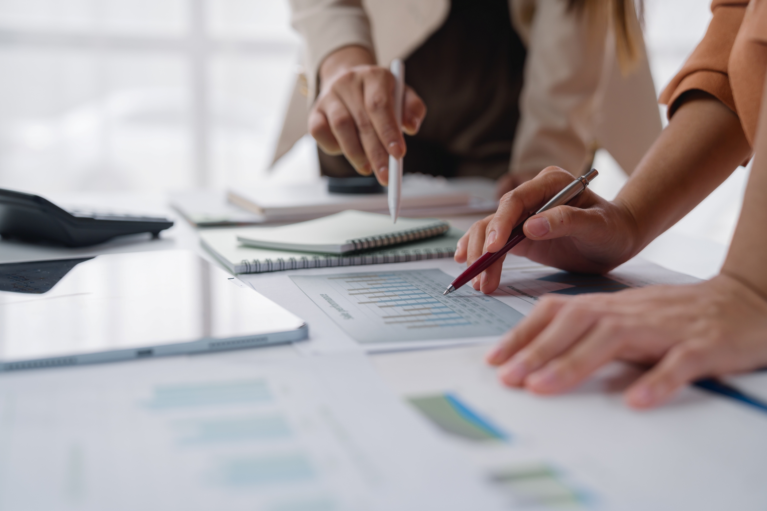 Close up of professionals looking at paper work and with pencil and calculator.