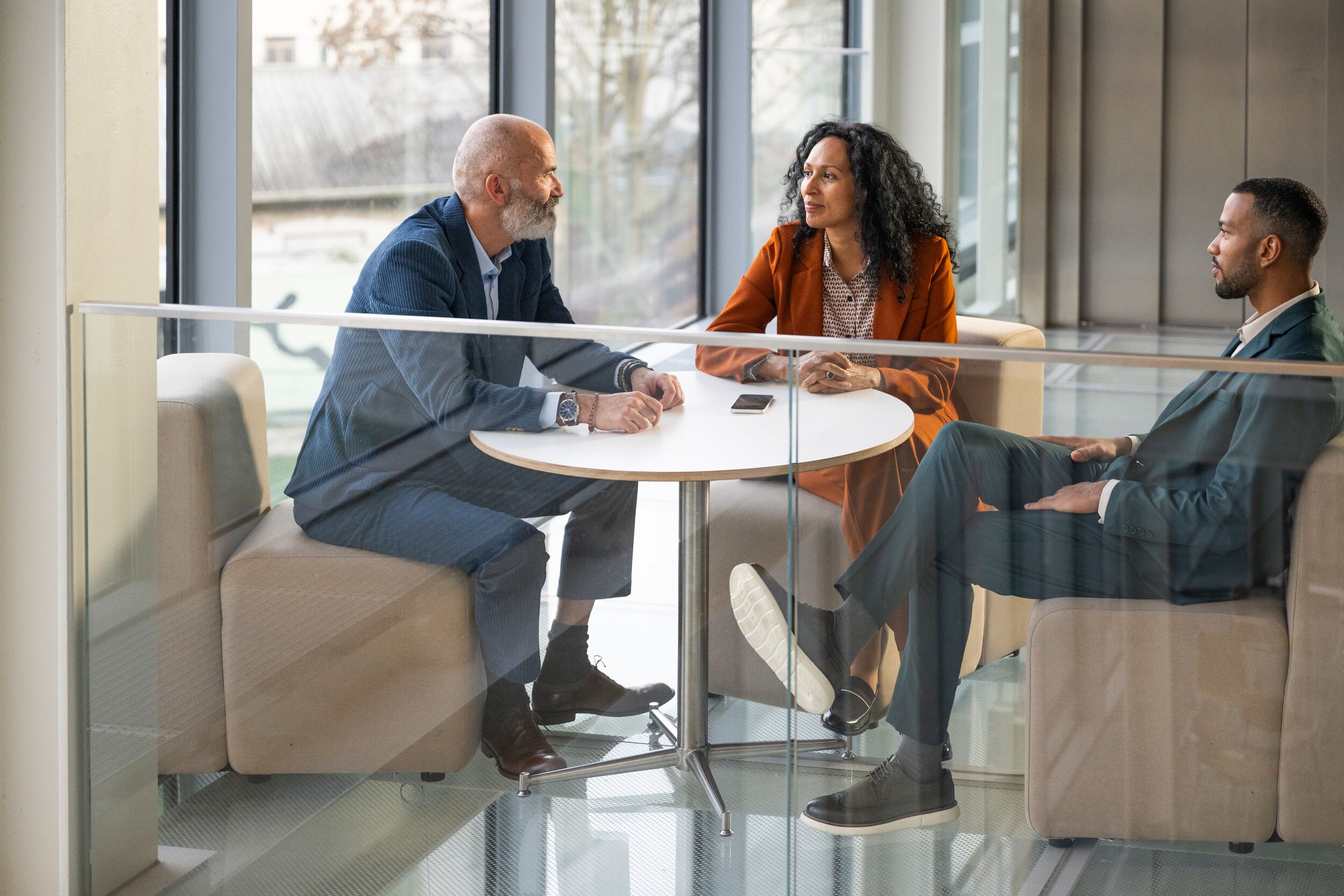 Three business people sitting at a table having a casual conversation.
