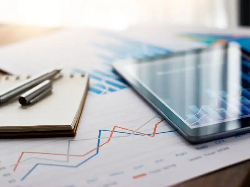 Business document report on paper and tablet with sales data and financial business growth graph on table background.