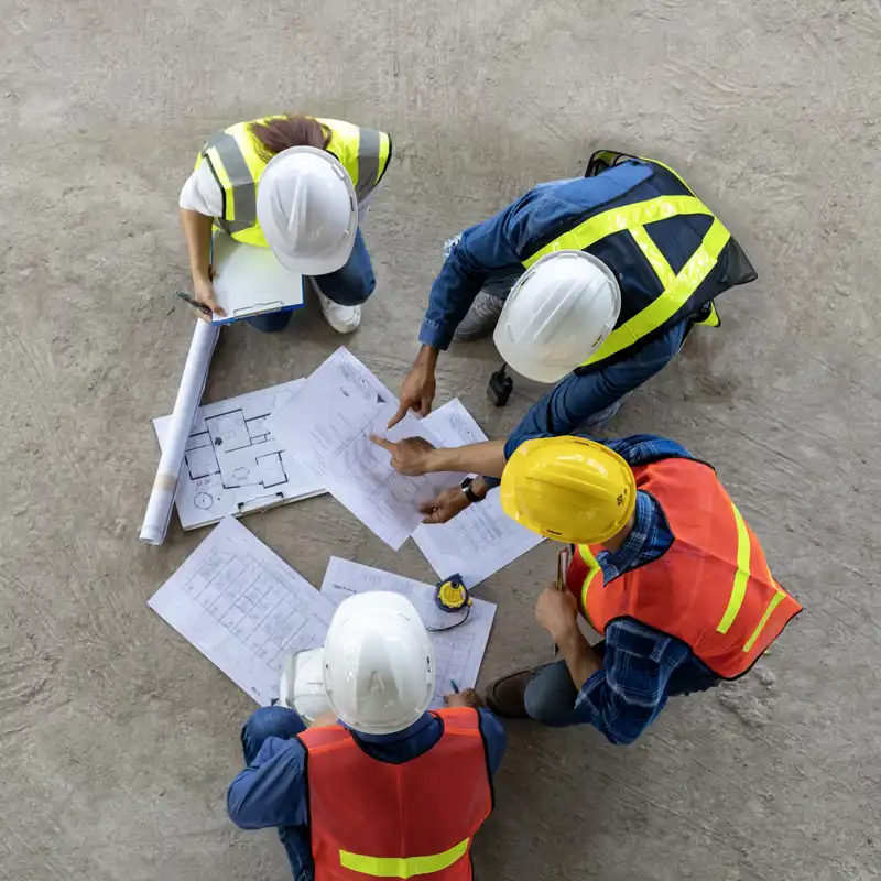 aerial view of construction workers looking at blueprints