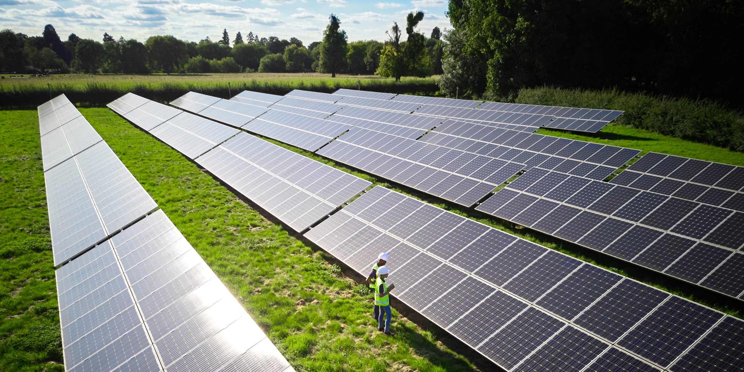 Workers inspecting solar panels in a rural field.