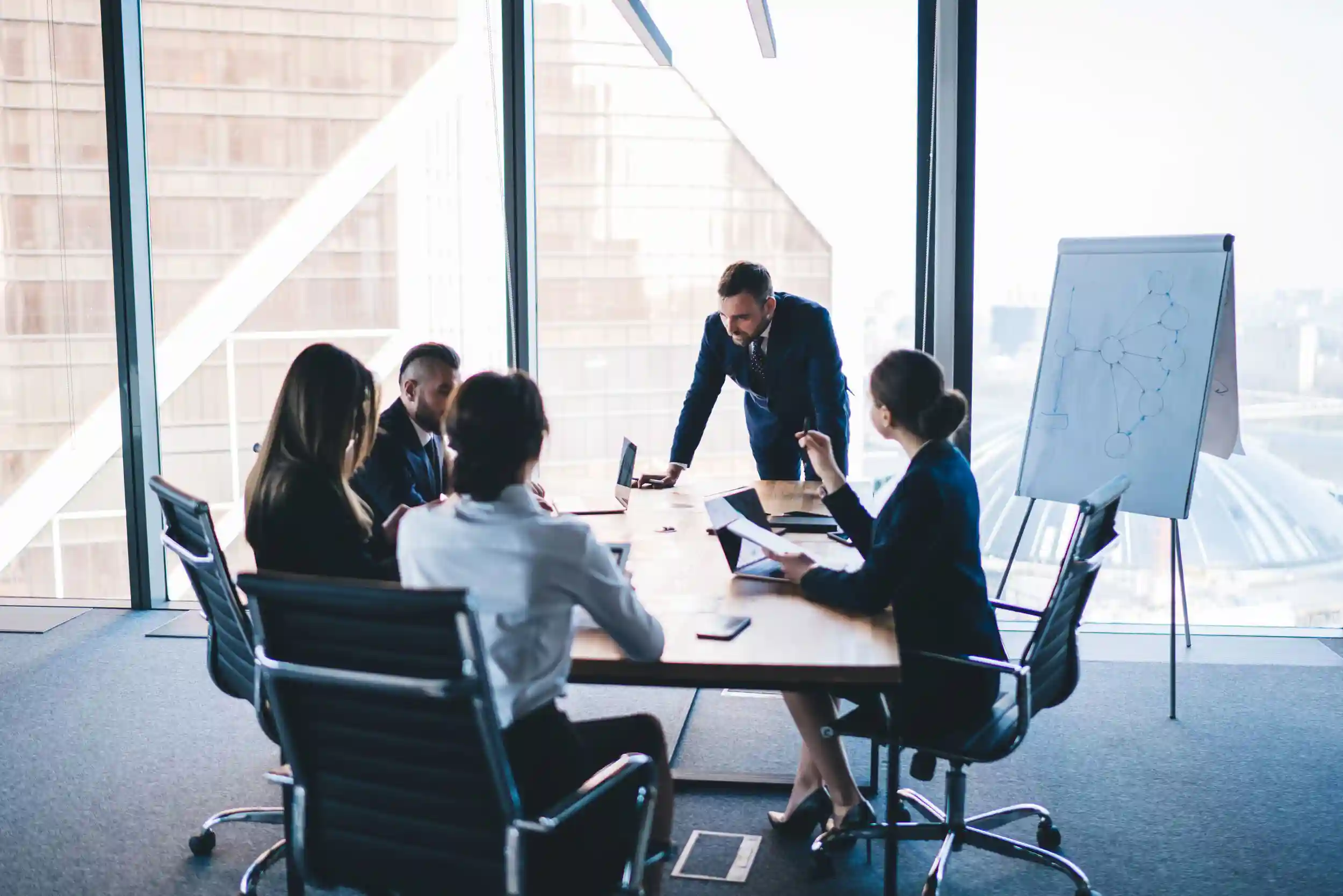 Group of coworkers in formal wear sitting at table in conference room and arguing about project of company development during meeting