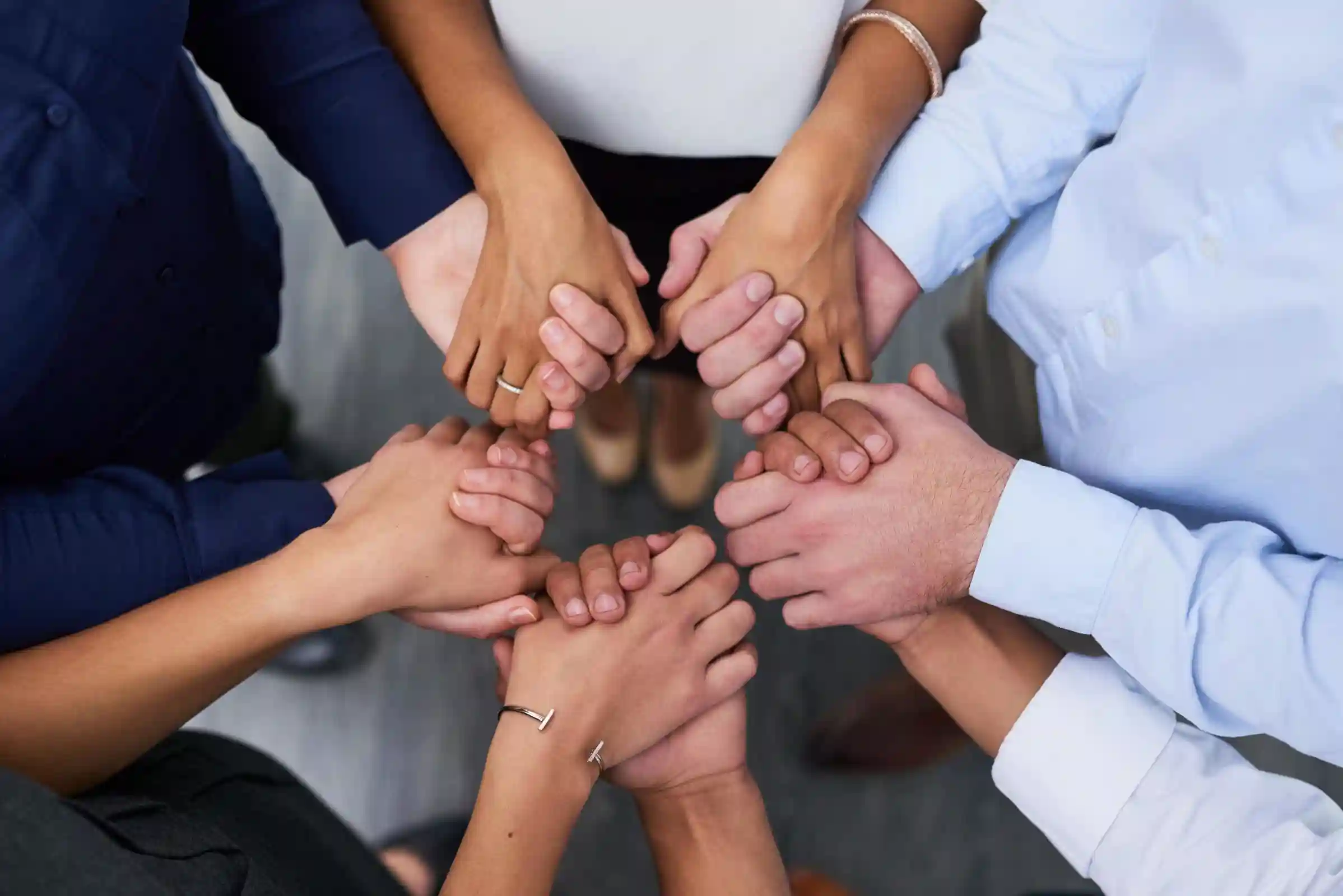 Overhead view of a group of diverse people holding hands.