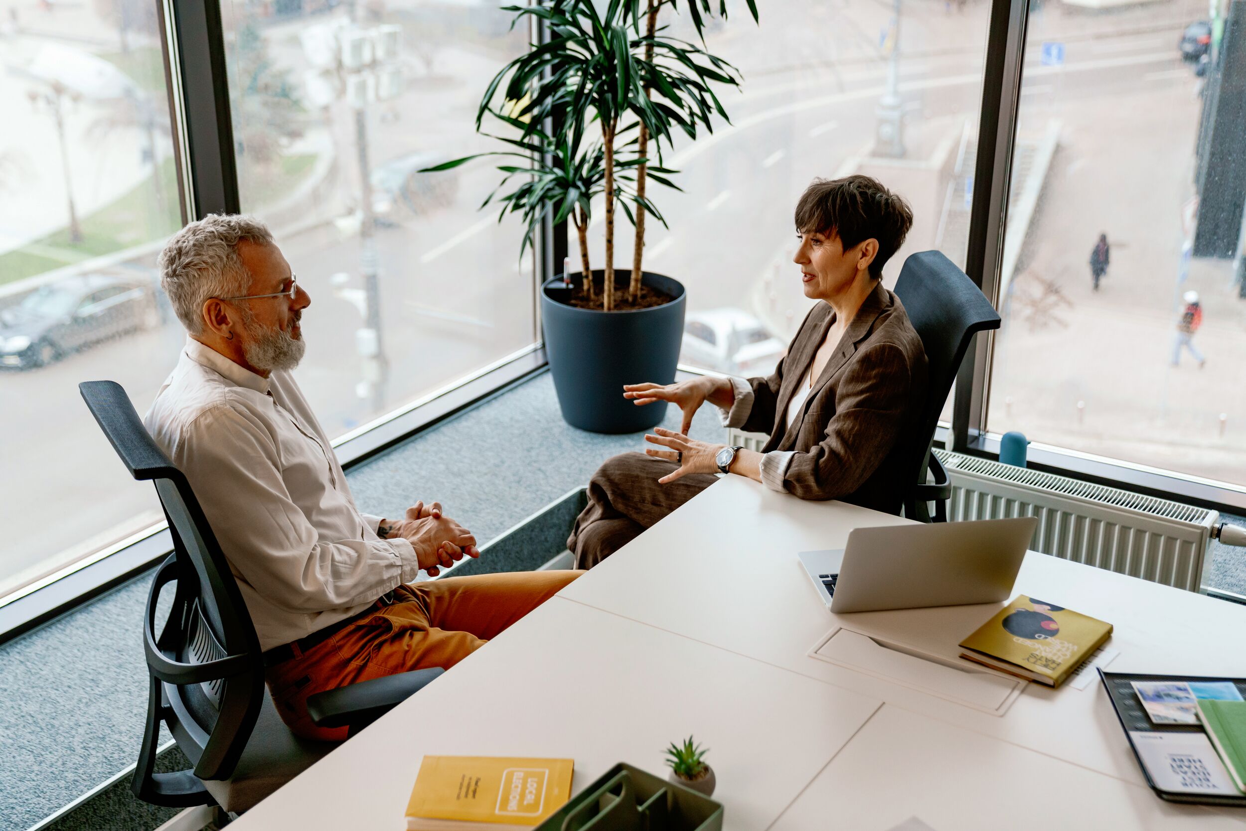Portrait of confident professional senior man and woman managers in formal wear sharing ideas during meeting in conference room.