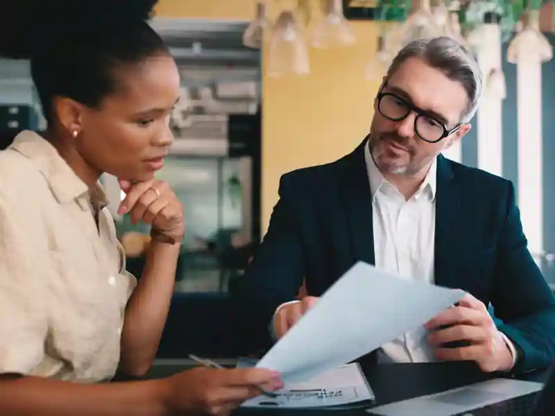 Business colleagues sitting at a restaurant reviewing paperwork.