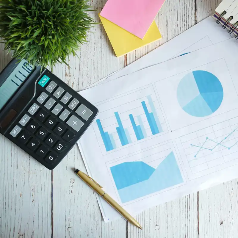 A desktop with a calculator, pencil, charts and notepads.