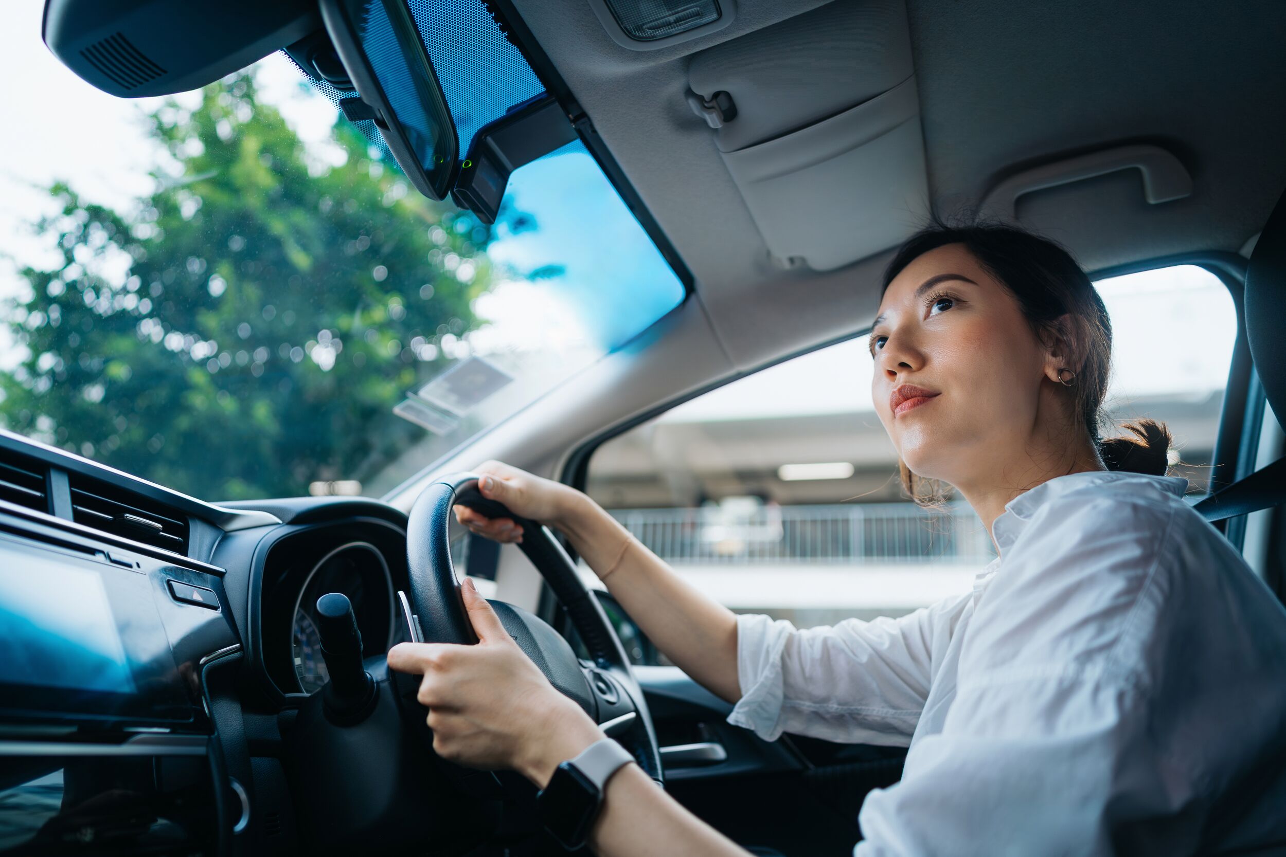 Young Asian woman driving a car in the city.