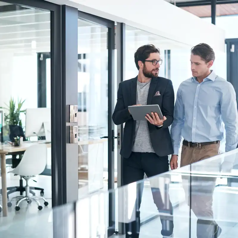 Two people looking at a laptop while walking.