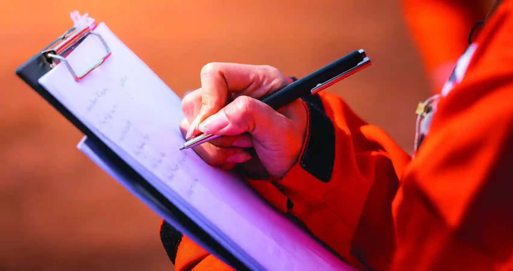 close up of an inspector holding a pen and clipboard