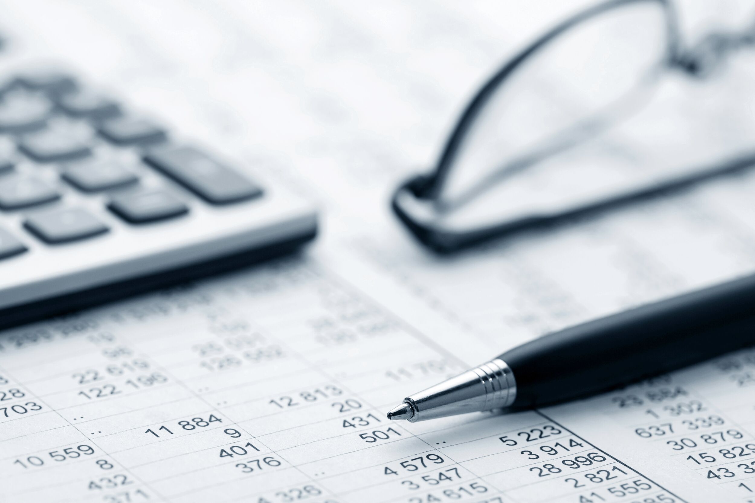 Closeup of accounting sheets, a calculator and a pair of glasses.