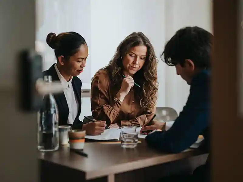 Coworkers review documents at a conference table.