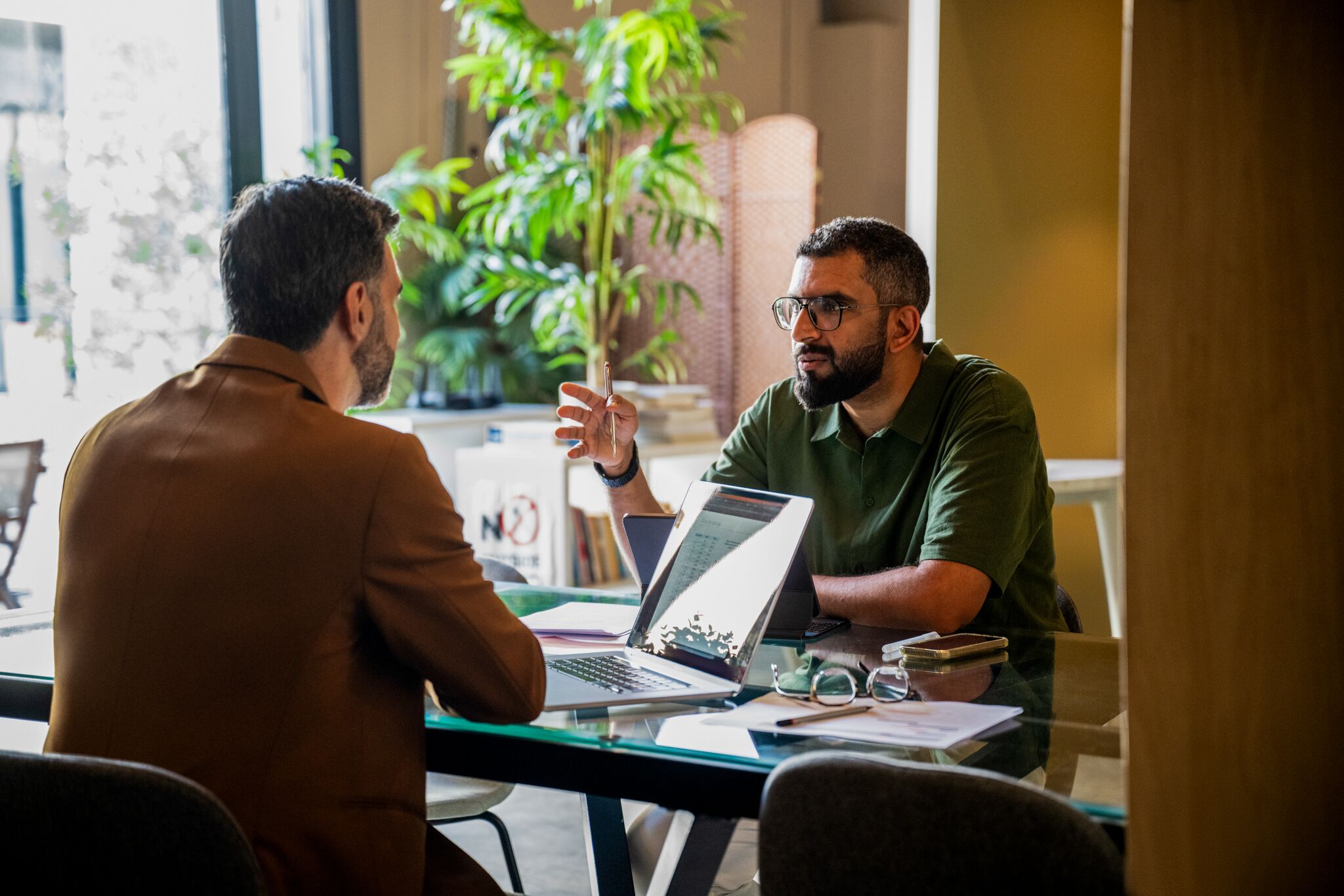Two businessmen sitting opposite each other in meeting with laptop.