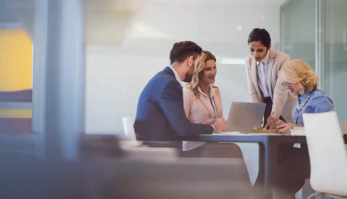 Four people have a meeting in a conference room.