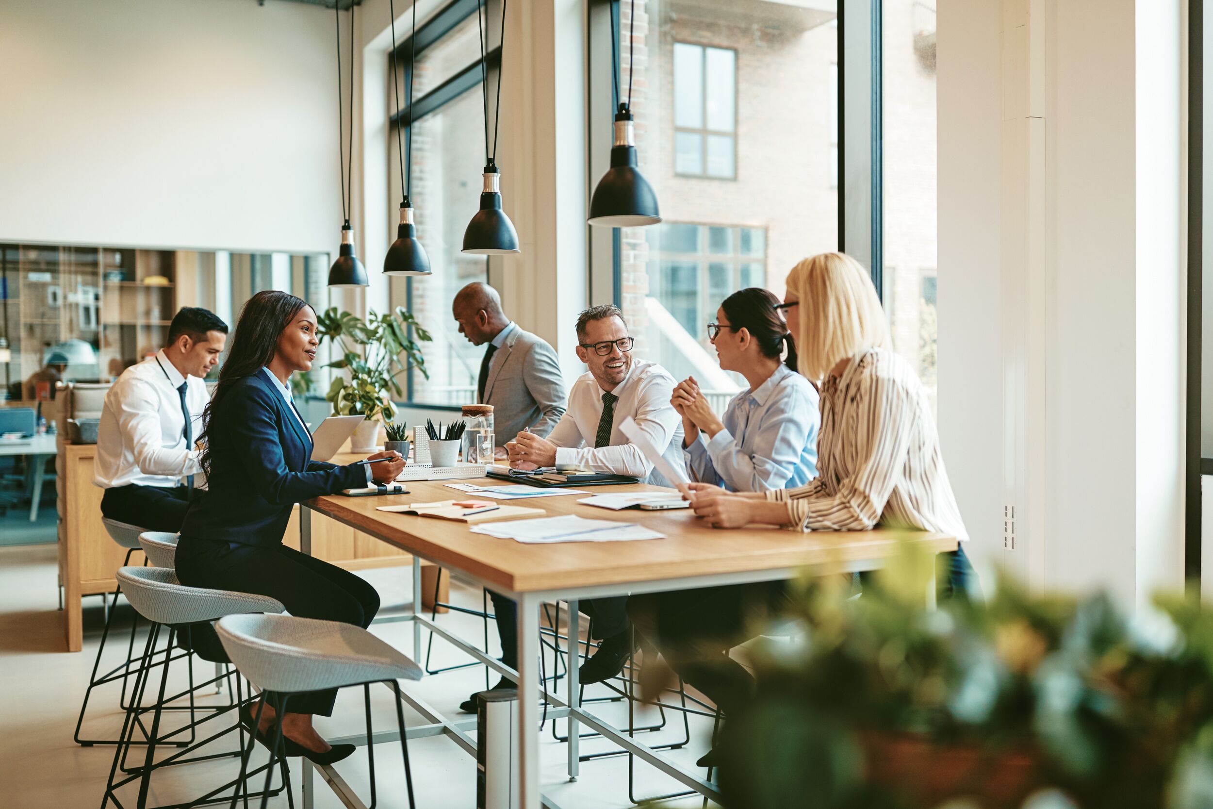 Smiling group of businesspeople discussing paperwork together while having a meeting around a table in a modern office.