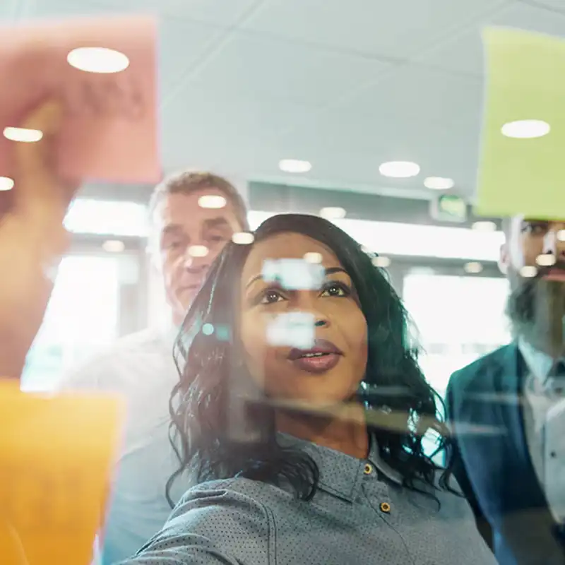 Co-workers placing post-it notes on to a board.