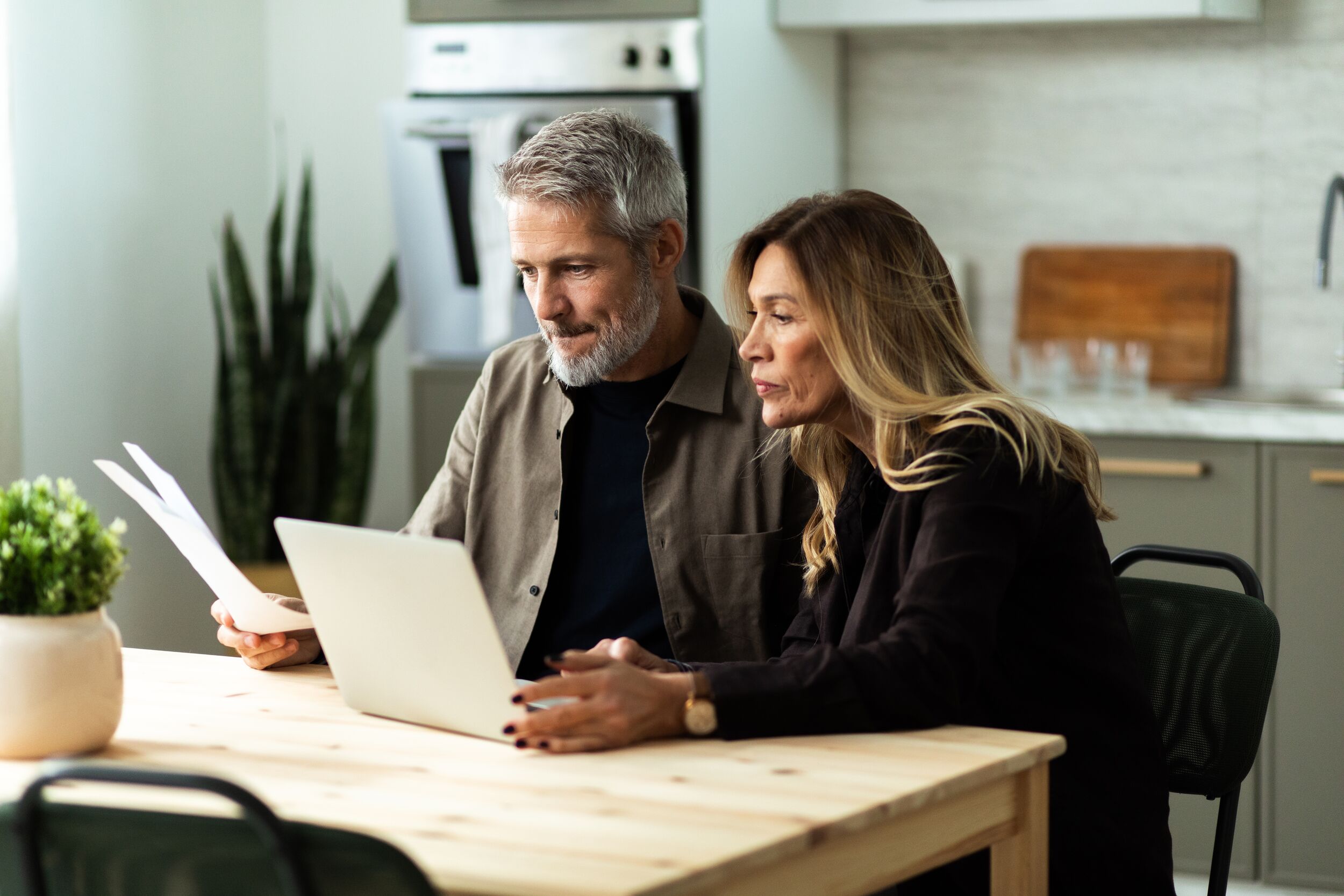 Mature couple planning home finances using laptop and documents.
